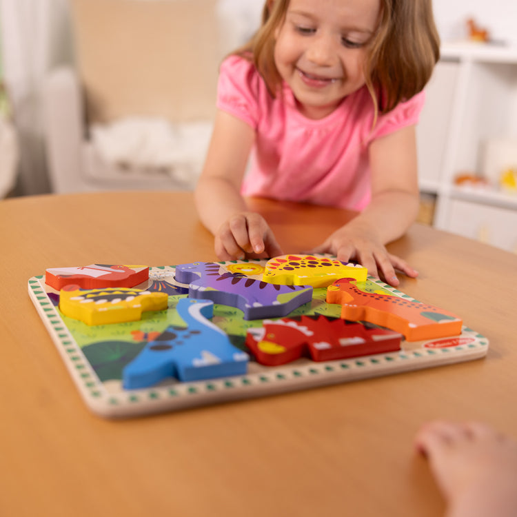 A kid playing with The Melissa & Doug Dinosaur Wooden Chunky Puzzle (7 pcs)