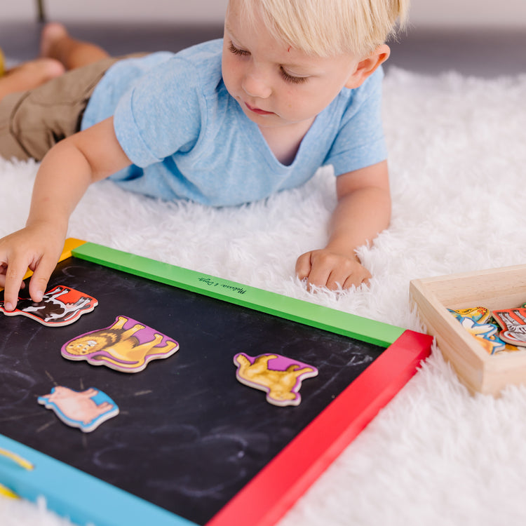 A kid playing with The Melissa & Doug 20 Wooden Animal Magnets in a Box