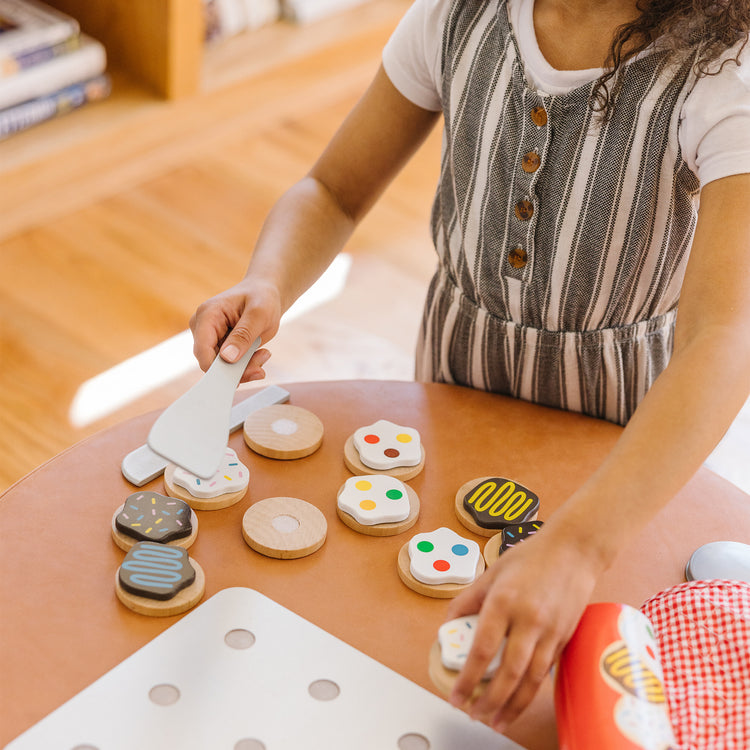 A kid playing with The Melissa & Doug Slice and Bake Wooden Cookie Play Food Set