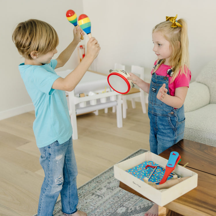 A kid playing with The Melissa & Doug Band-in-a-Box Clap! Clang! Tap! - 10-Piece Musical Instrument Set