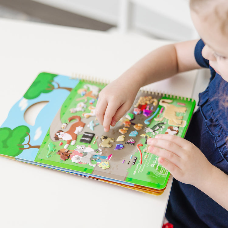 A kid playing with The Melissa & Doug Pet Shop Puffy Sticker Set With 115 Reusable Stickers