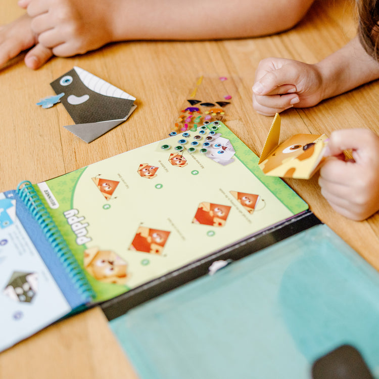 A kid playing with The Melissa & Doug On the Go Origami Animals Craft Activity Set - 38 Stickers, 40 Origami Papers