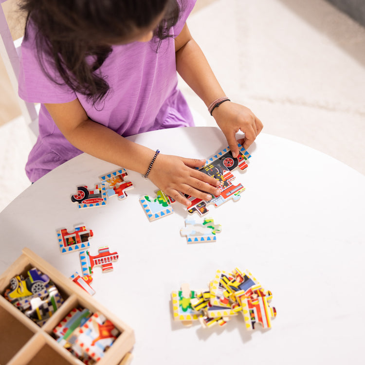 A kid playing with The Melissa & Doug Vehicles 4-in-1 Wooden Jigsaw Puzzles in a Storage Box (48 pcs)