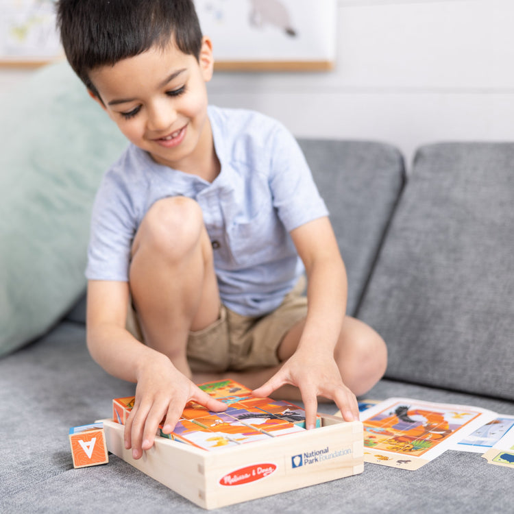 A kid playing with The Melissa & Doug National Parks Alphabet & Animals 24-Piece Cube Puzzle (Everglades, Arches, Yellowstone)