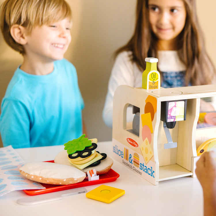 A kid playing with The Melissa & Doug Wooden Slice & Stack Sandwich Counter with Deli Slicer – 56-Piece Pretend Play Food Pieces