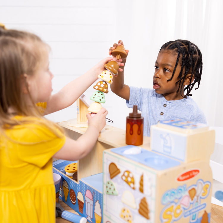 A kid playing with The Melissa & Doug Wooden Cool Scoops Ice Creamery Play Food Toy