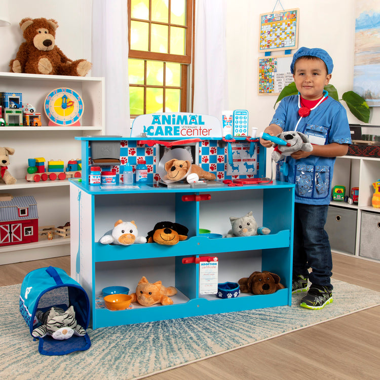 A kid playing with The Melissa & Doug Animal Care Veterinarian and Groomer Wooden Activity Center for Plush Stuffed Pets (Not Included)