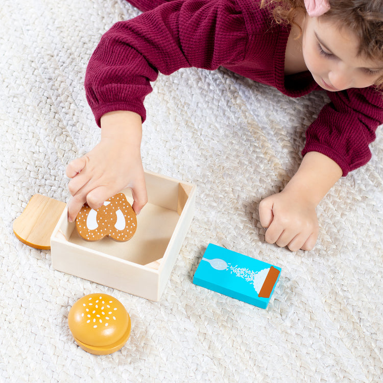 A kid playing with The Melissa & Doug Wooden Food Groups Play Food Set – Grains