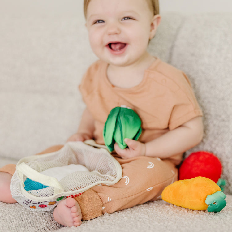 A kid playing with The Melissa & Doug Multi-Sensory Market Basket Fill & Spill Infant Toy