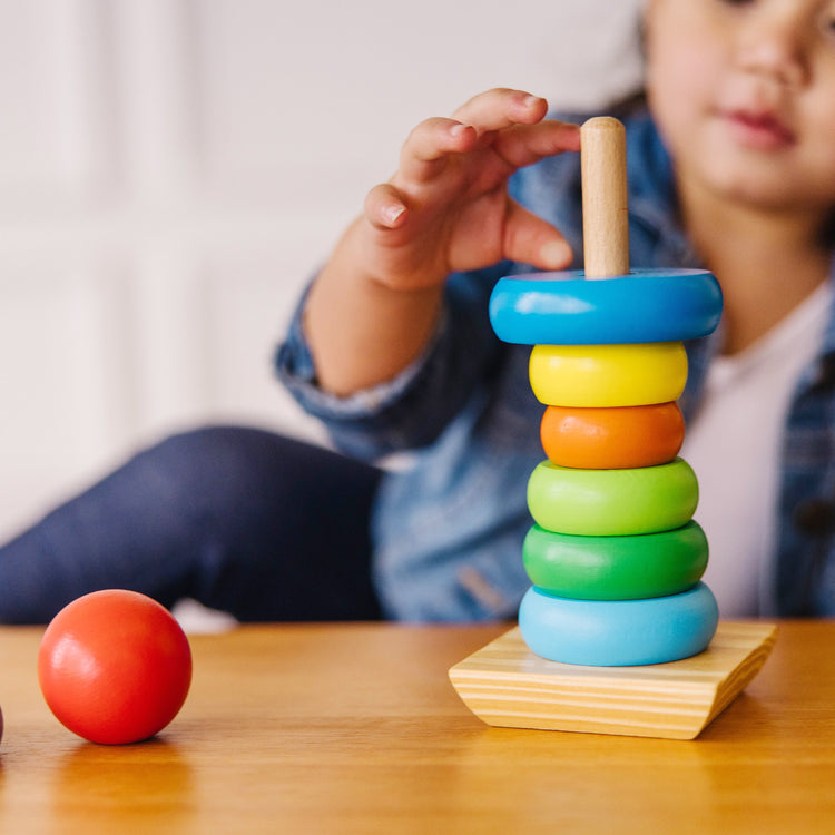 A kid playing with The Melissa & Doug Rainbow Stacker Wooden Ring Educational Toy