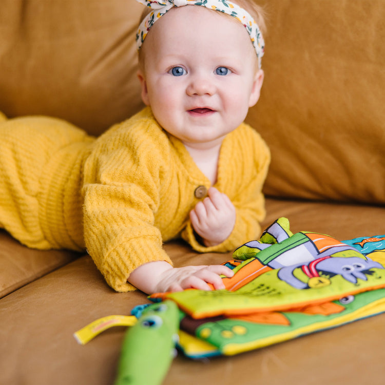 A kid playing with The Melissa & Doug Soft Activity Baby Book - Whose Feet?