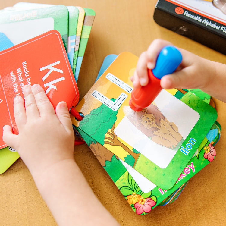 A kid playing with The Melissa & Doug On the Go Water Wow! Reusable Water-Reveal Activity Cards - Alphabet and Animals