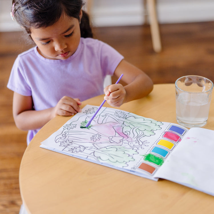 A kid playing with The Melissa & Doug Paint With Water - Princess, 20 Perforated Pages With Spillproof Palettes