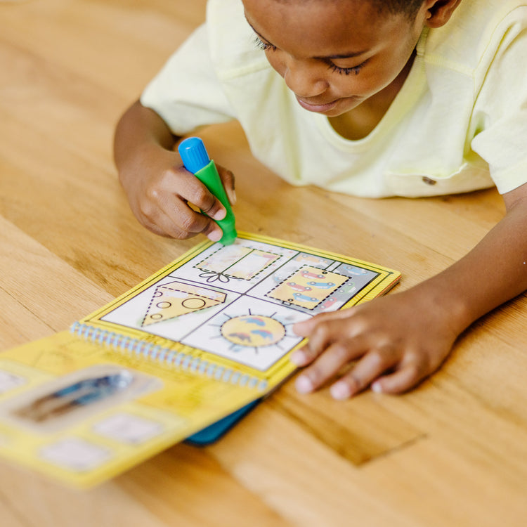 A kid playing with The Melissa & Doug On the Go Water Wow! Reusable Water-Reveal Activity Pad - Colors, Shapes