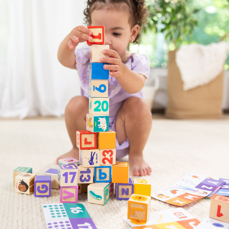 A kid playing with The Melissa & Doug Ms. Rachel Letter, Number, and Game Wooden Learning Blocks with Activity Cards for Girls and Boys Toddlers Ages 18 Months+