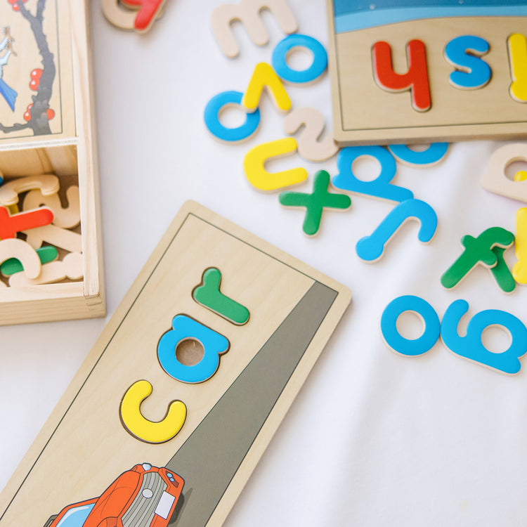 A kid playing with The Melissa & Doug See & Spell Wooden Educational Toy With 8 Double-Sided Spelling Boards and 64 Letters