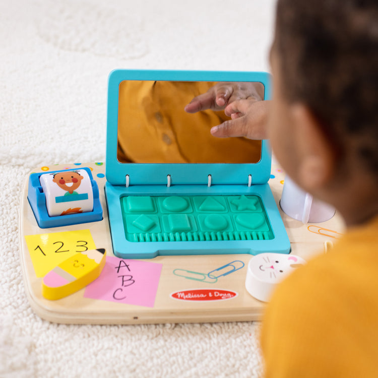 A kid playing with The Melissa & Doug Wooden Work & Play Desktop Activity Board Infant and Toddler Sensory Toy