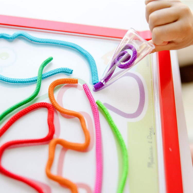 A kid playing with The Melissa & Doug Rainbow Cord Picture And Pattern Maker Draw with Cords Activity – 39 Cords, 6 Double-Sided Cards to Trace