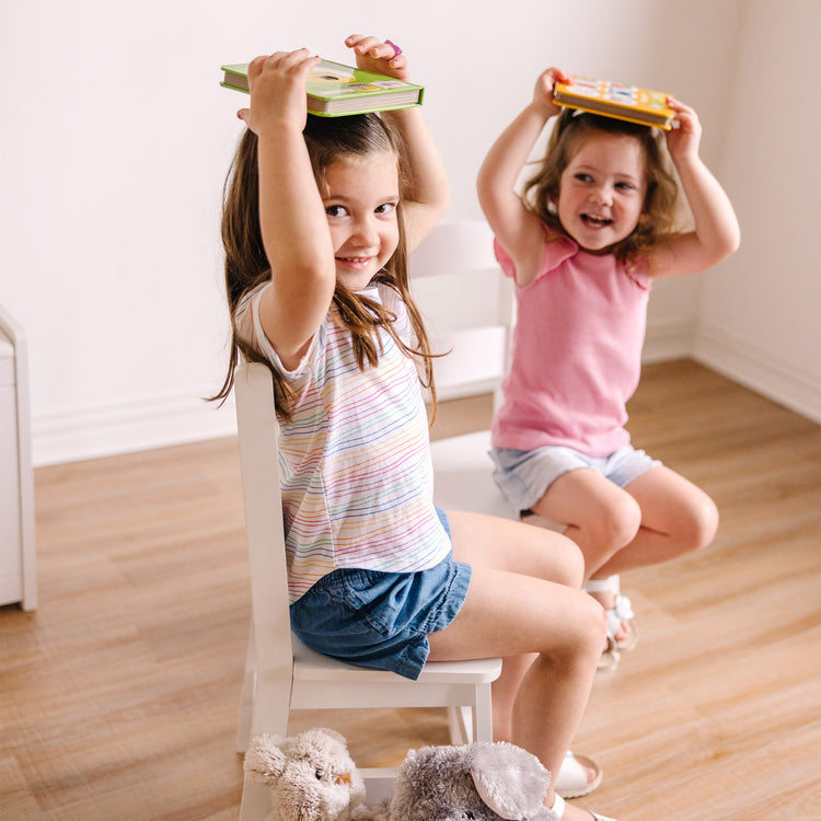 A kid playing with The Melissa & Doug Wooden Chairs, Set of 2 - White Furniture for Playroom