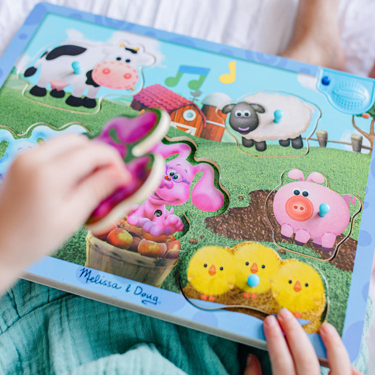 A kid playing with The Melissa & Doug Blue's Clues & You! Wooden Sound Puzzle - Musical Farm (6 Pieces)