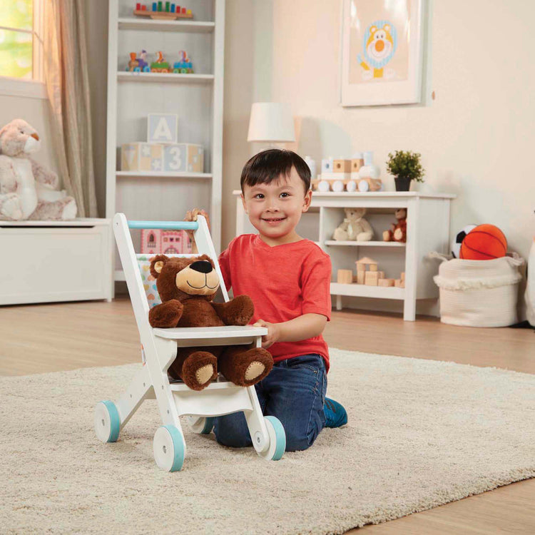 A kid playing with The Melissa & Doug Mine to Love Wooden Play Stroller for Dolls, Stuffed Animals - White (18”H x 8”W x 11”D Assembled)