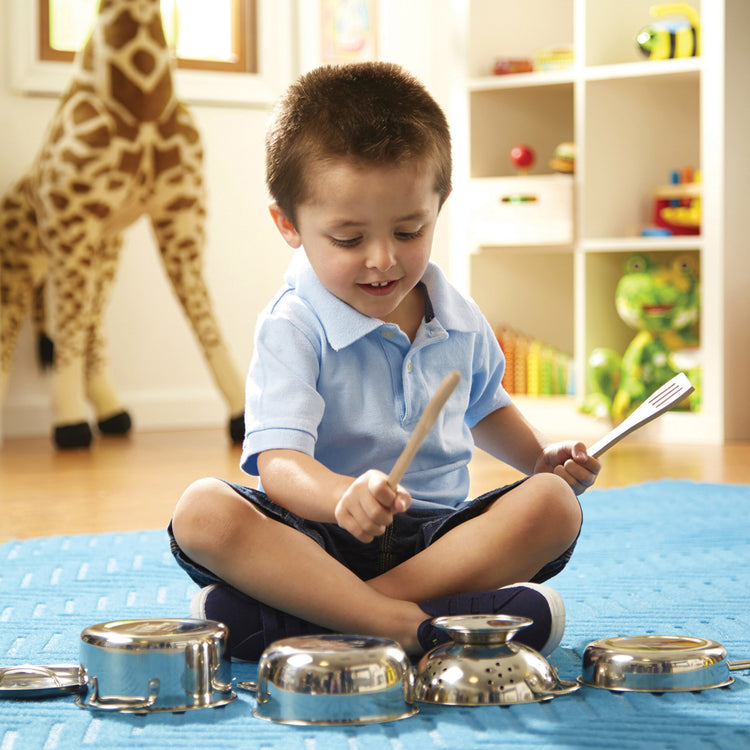 A kid playing with The Melissa & Doug Stainless Steel Pots and Pans Pretend Play Kitchen Set for Kids (8 pcs)