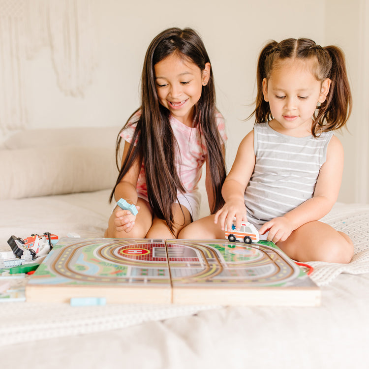 A kid playing with The Melissa & Doug 18-Piece Wooden Take-Along Tabletop Town, 4 Rescue Vehicles, Play Pieces, Bridge