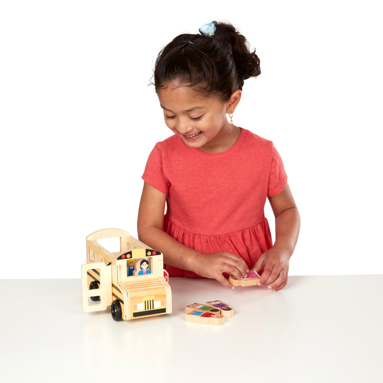 A child on white background with The Melissa & Doug School Bus Wooden Play Set With 7 Play Figures