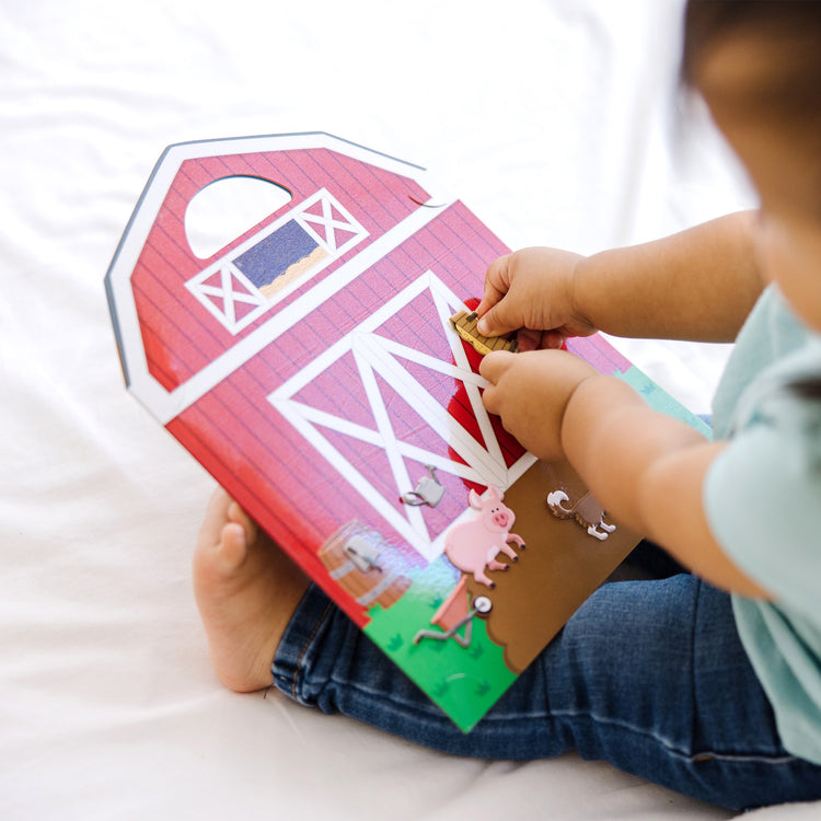 A kid playing with The Melissa & Doug Puffy Sticker Play Set - On the Farm - 52 Reusable Stickers, 2 Fold-Out Scenes