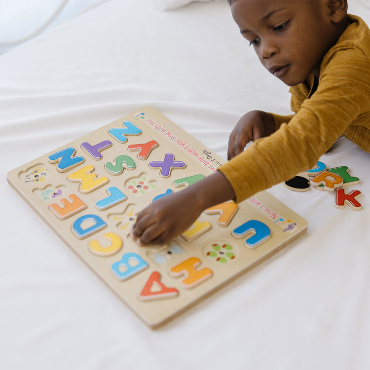 A kid playing with The Melissa & Doug Wooden Alphabet Sound Puzzle - Wooden Puzzle With Sound Effects (26 pcs)