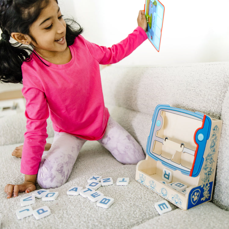 A kid playing with The Melissa & Doug PAW Patrol Wooden See & Spell Pup Pad Game