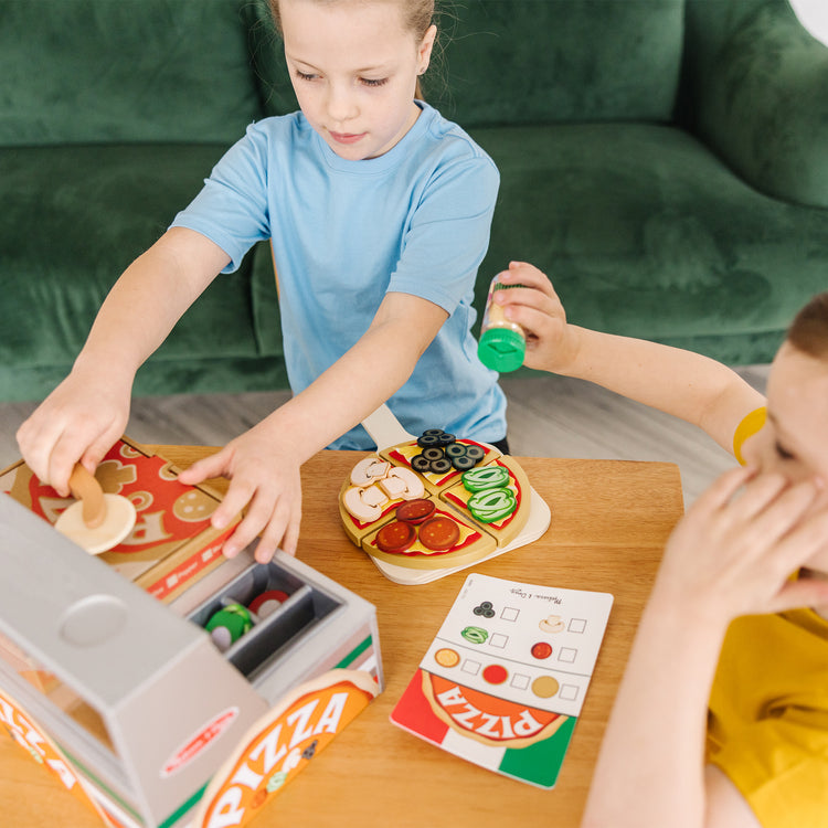 A kid playing with The Melissa & Doug Top & Bake Wooden Pizza Counter Play Set (41 Pcs)