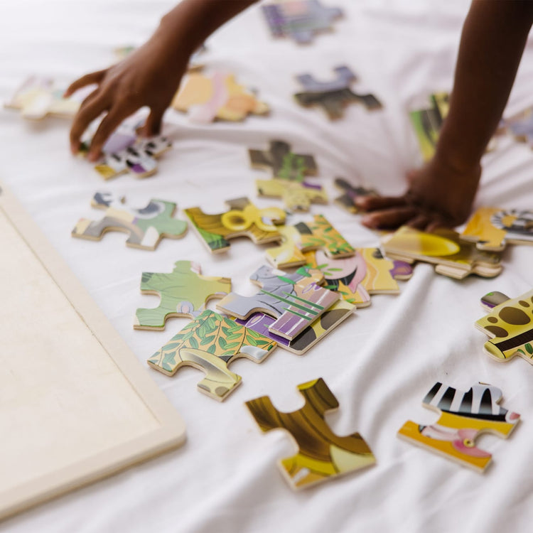 A kid playing with the Melissa & Doug African Plains Safari Wooden Jigsaw Puzzle With Storage Tray (24 pcs)