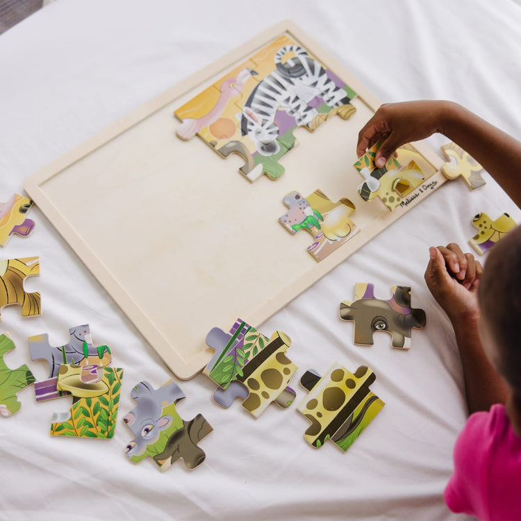 A kid playing with the Melissa & Doug African Plains Safari Wooden Jigsaw Puzzle With Storage Tray (24 pcs)