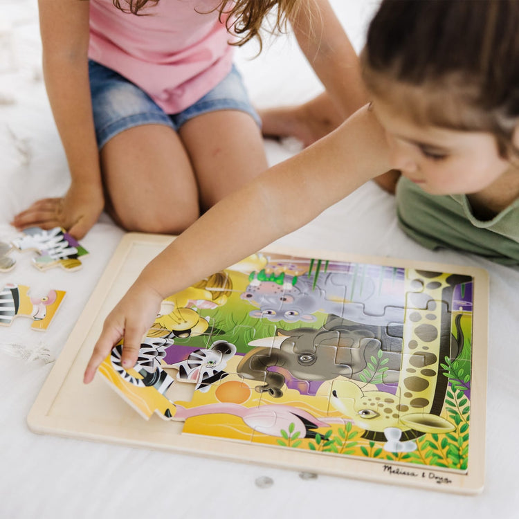 A kid playing with the Melissa & Doug African Plains Safari Wooden Jigsaw Puzzle With Storage Tray (24 pcs)