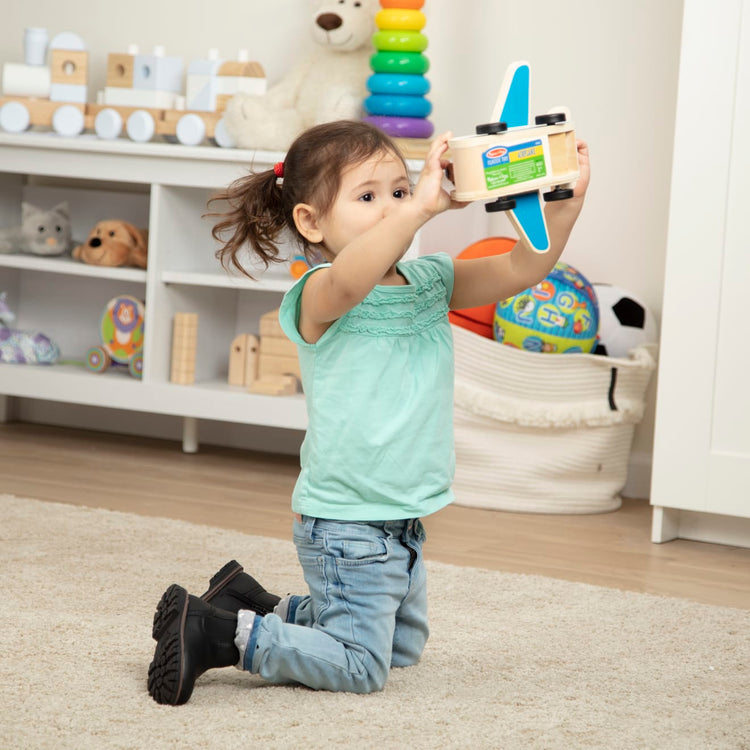 A kid playing with the Melissa & Doug Wooden Airplane Play Set With 4 Play Figures and 4 Suitcases