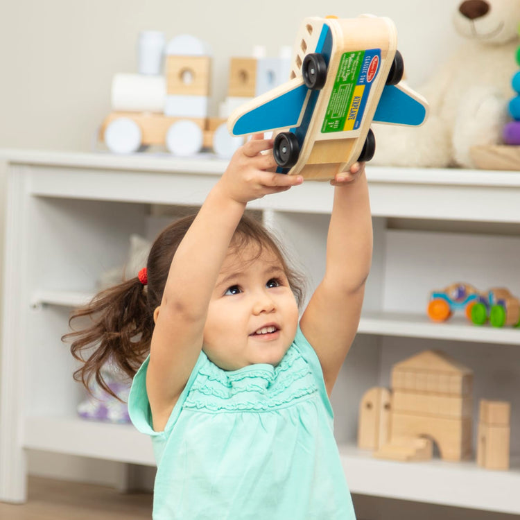 A kid playing with the Melissa & Doug Wooden Airplane Play Set With 4 Play Figures and 4 Suitcases