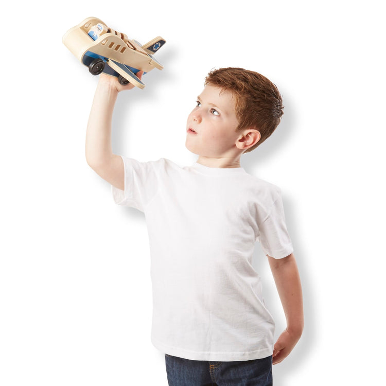 A child on white background with the Melissa & Doug Wooden Airplane Play Set With 4 Play Figures and 4 Suitcases