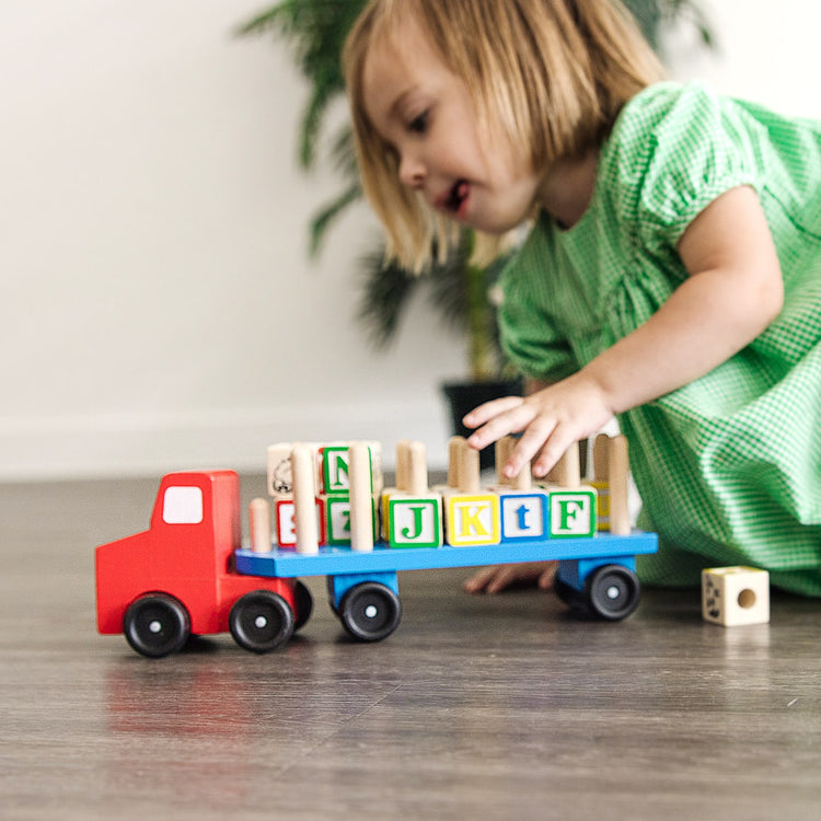 A kid playing with the Melissa & Doug Alphabet Blocks Wooden Truck Educational Toy