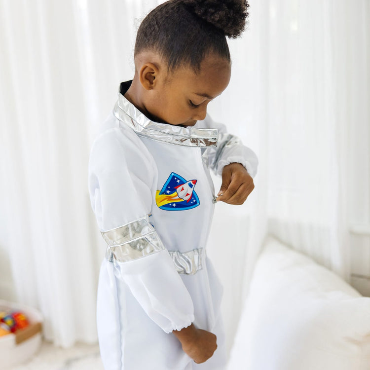 A kid playing with the Melissa & Doug Astronaut Costume Role Play Space Set (5 pcs) - Jumpsuit, Helmet, Gloves, Name Tag