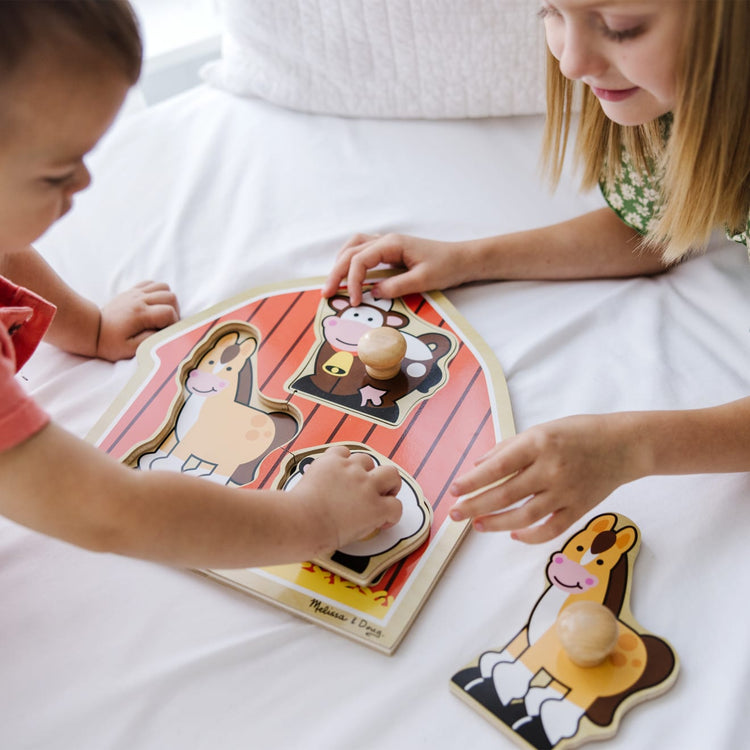 A kid playing with the Melissa & Doug Barnyard Animals Jumbo Knob Wooden Puzzle - Horse, Cow, and Sheep