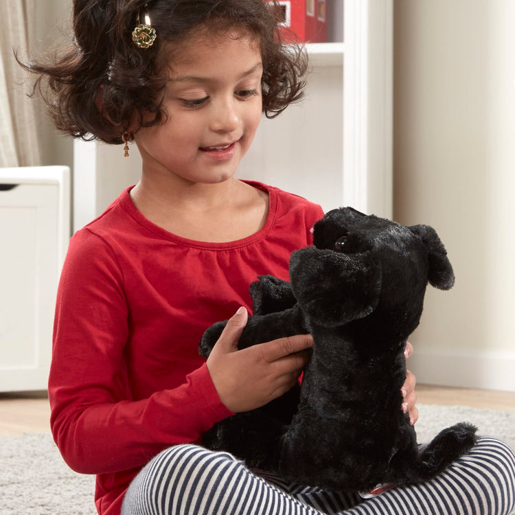 A kid playing with the Melissa & Doug Benson Black Lab - Stuffed Animal Puppy Dog