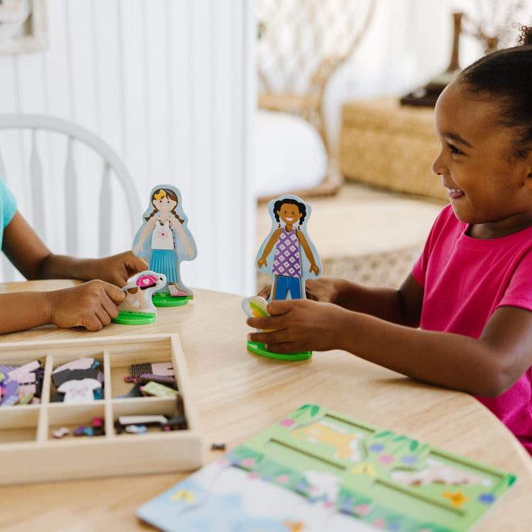 A kid playing with the Melissa & Doug Best Friends Magnetic Dress-Up Wooden Dolls Pretend Play Set (78 pcs)