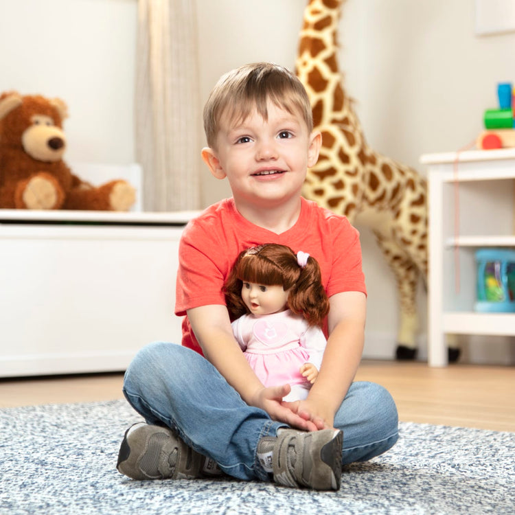 A kid playing with the Melissa & Doug Mine to Love Brianna 12-Inch Soft Body Baby Doll With Hair and Outfit