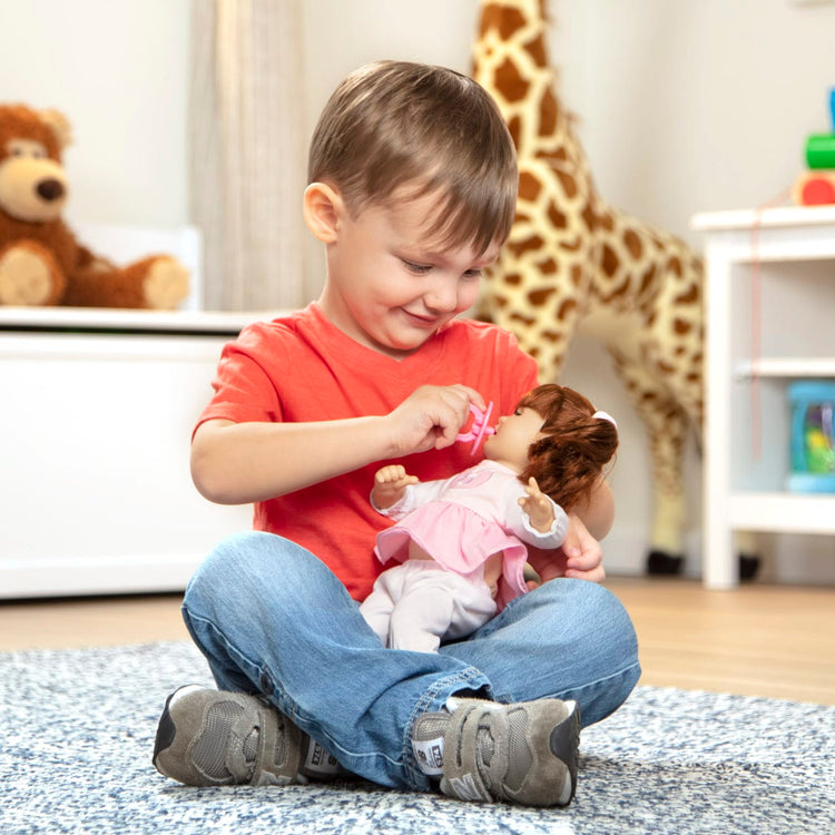 A kid playing with the Melissa & Doug Mine to Love Brianna 12-Inch Soft Body Baby Doll With Hair and Outfit