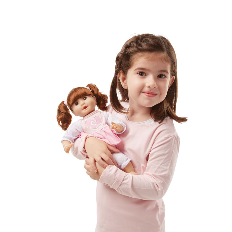 A child on white background with the Melissa & Doug Mine to Love Brianna 12-Inch Soft Body Baby Doll With Hair and Outfit