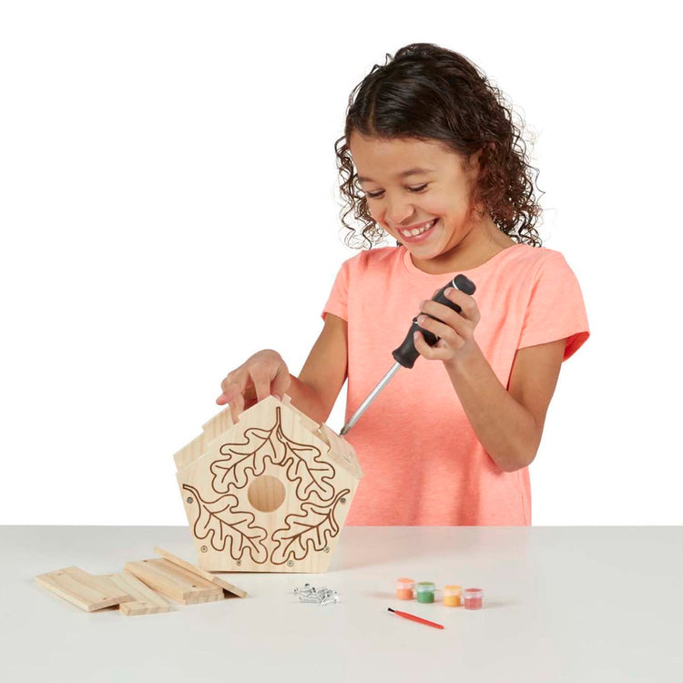 A child on white background with the Melissa & Doug Created by Me! Birdhouse Build-Your-Own Wooden Craft Kit