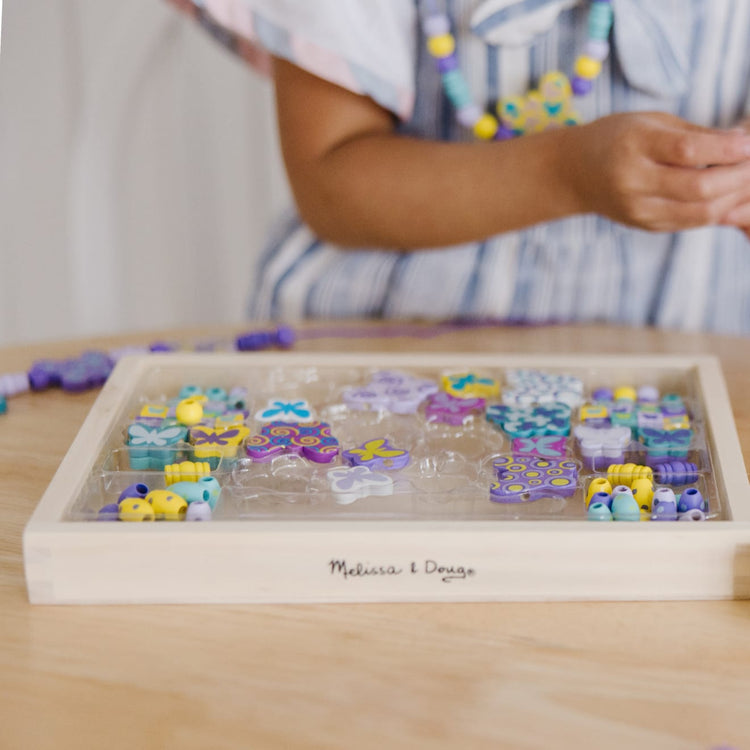 The front of the box for the Melissa & Doug Created by Me! Butterfly Beads Wooden Bead Kit, 150+ Beads for Jewelry-Making