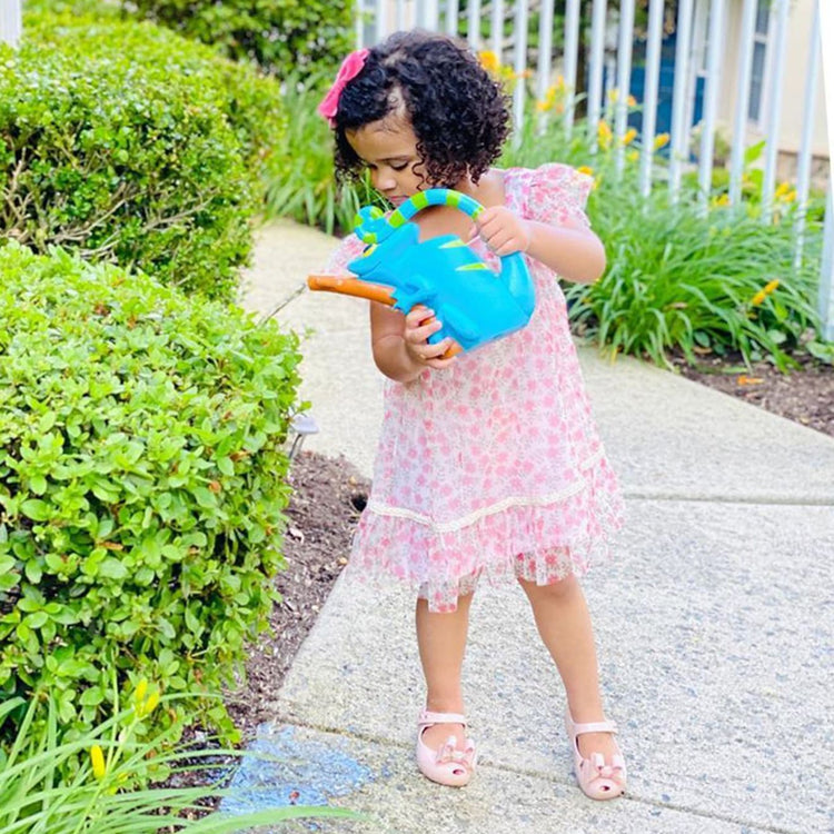 A kid playing with the Melissa & Doug Sunny Patch Camo Chameleon Watering Can With Tail Handle and Branch-Shaped Spout