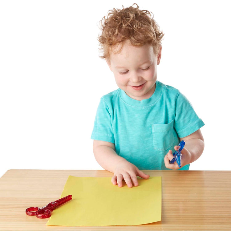 A child on white background with the Melissa & Doug Child-Safe Scissors - Child-Friendly Scissors, Lefty and Righty, Set of 2